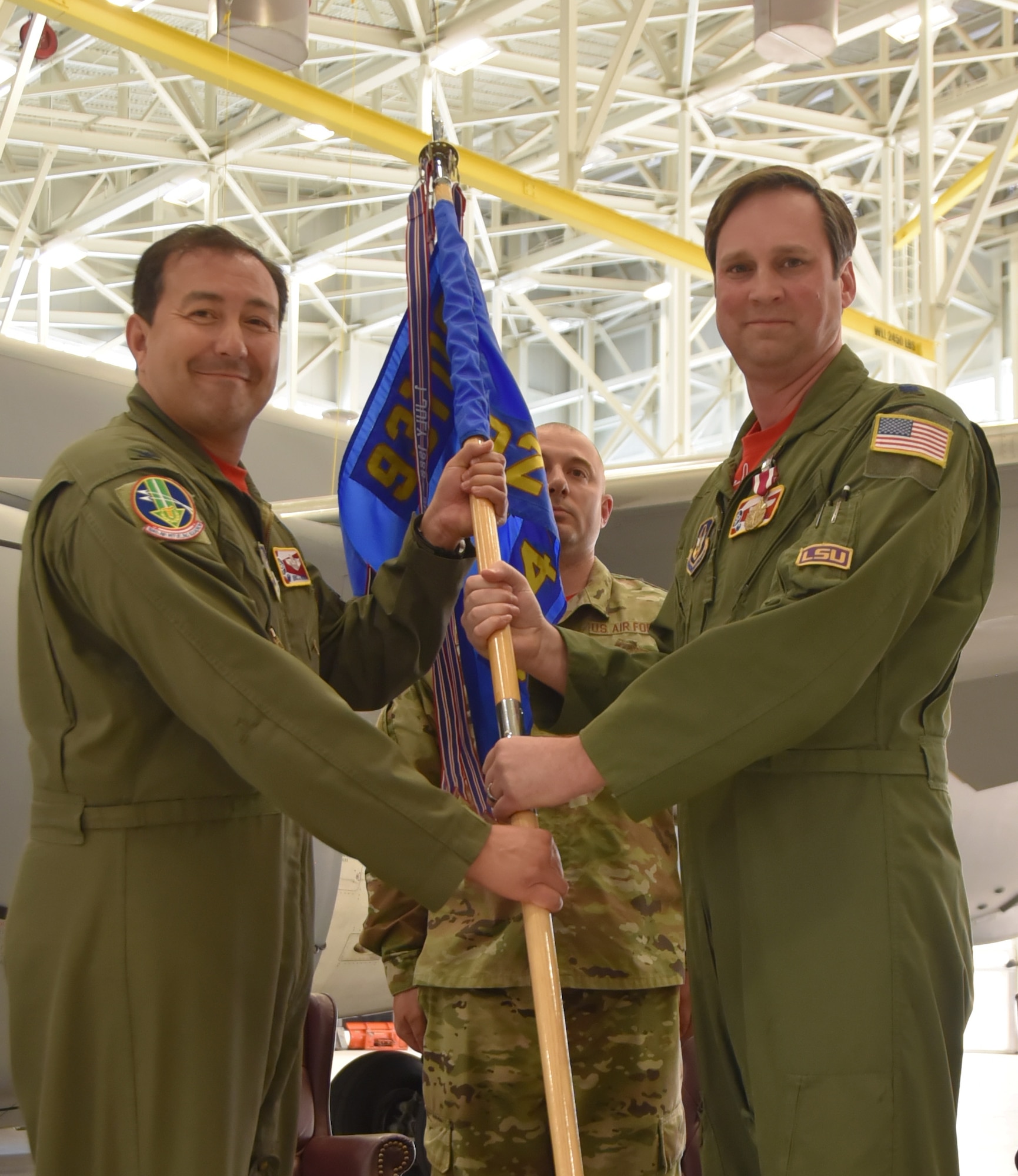 (Left to right) Col. Eric Rivero, 931st Operations Group commander, takes the guidon from Lt. Col. Scot Stewart, during an official change of command ceremony.