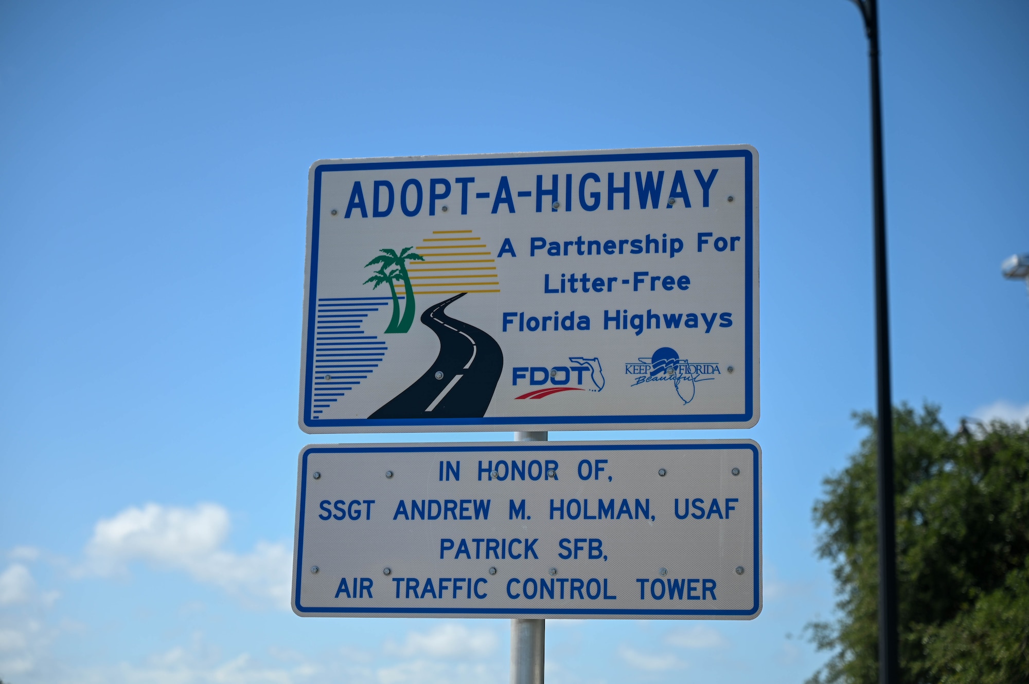 An Adopt-A-Highway sign in honor of Staff Sgt. Andrew Holman 45th LRS air traffic controller on April 21, 2023 in Melbourne, Fla. 45th LRS adopted the section of highway that Holman had passed away on. (U.S. Space Force photo by Senior Airman Samuel Becker)