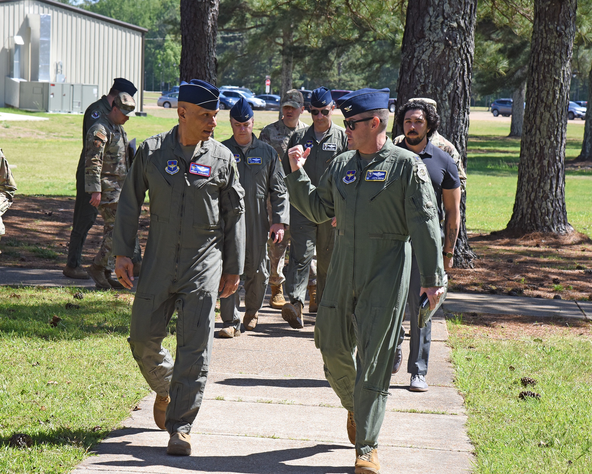 Lt. Gen. Brian Robinson talks to 14th Flying Training Wing leadership while walking down a sidewalk at Columbus AFB, Mississippi.
