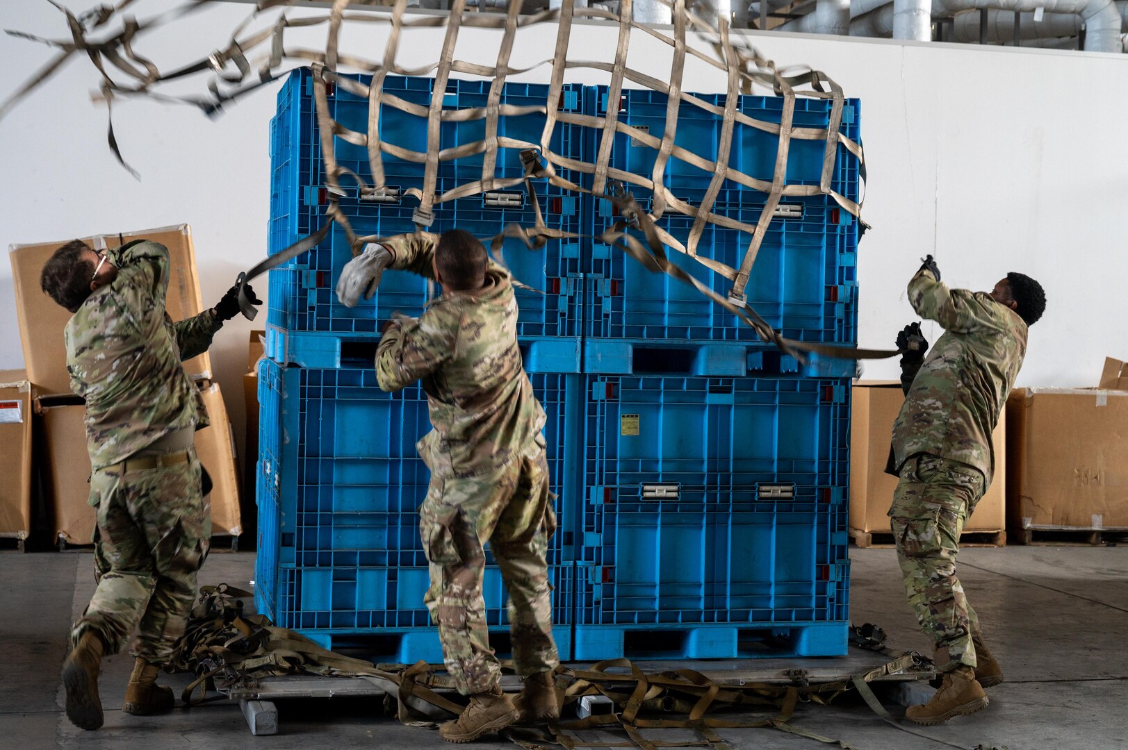 Service members throw a net on a pallet.