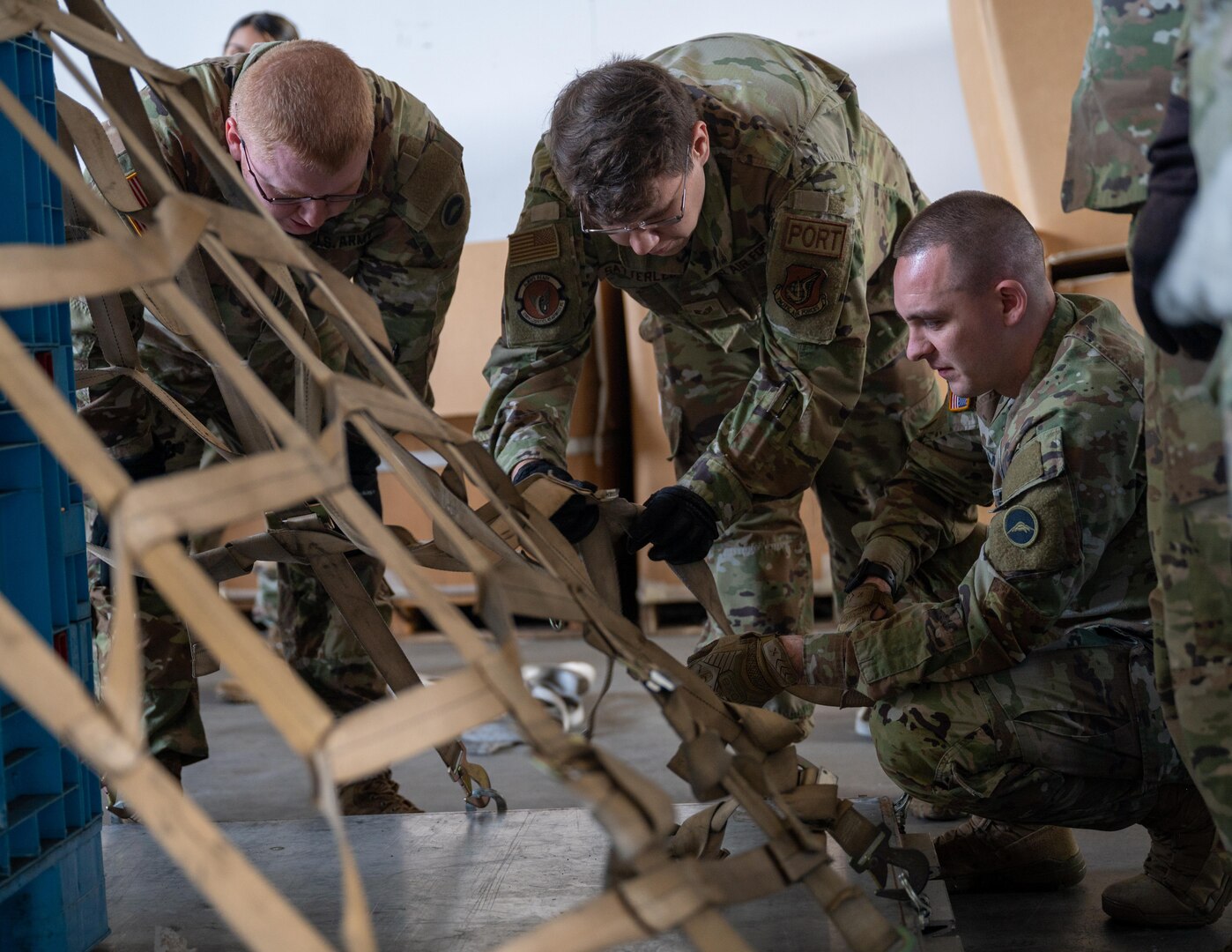 Service members secure a net to a pallet.