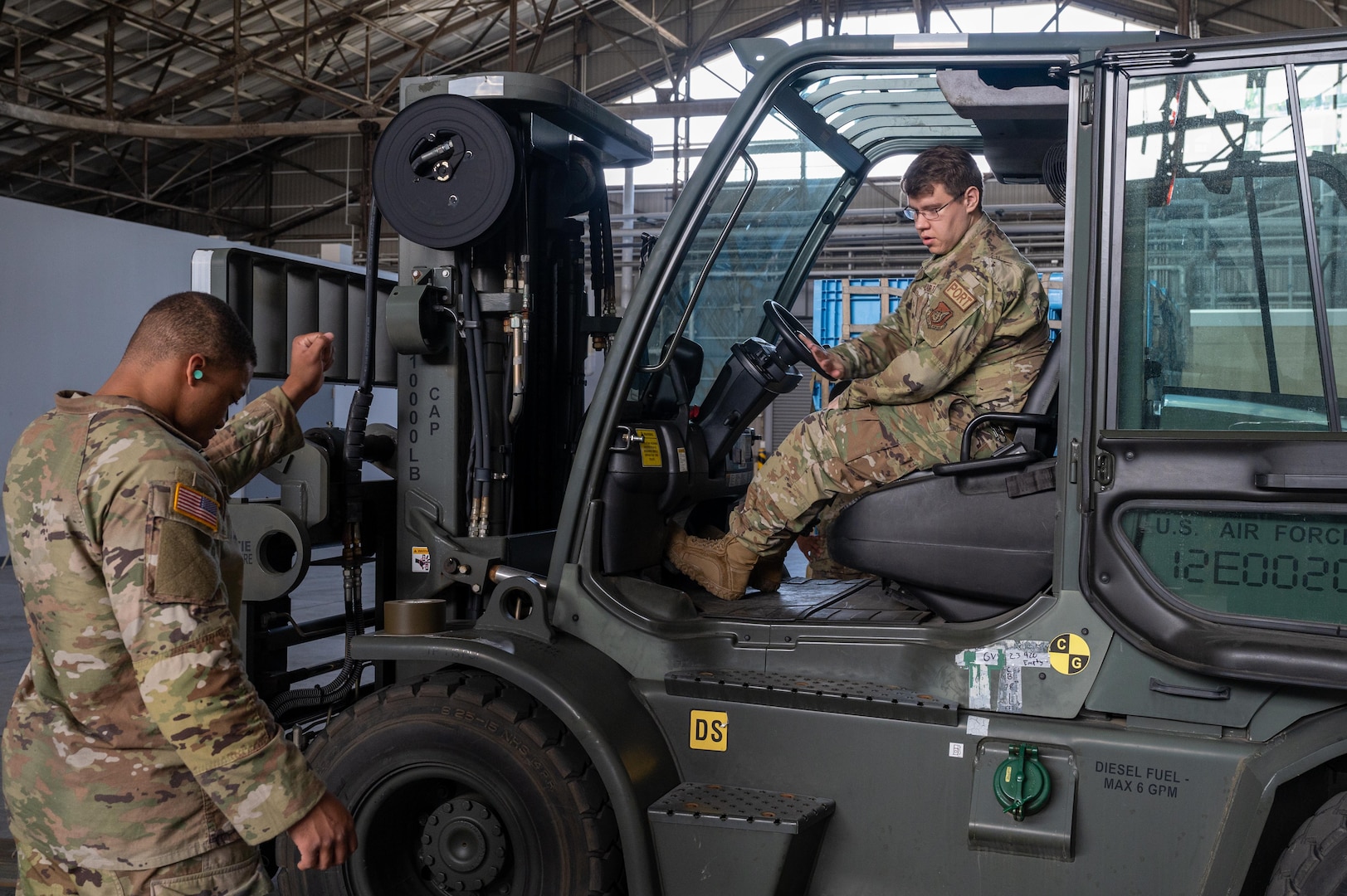 A service member helps guide a forklift onto a scale.