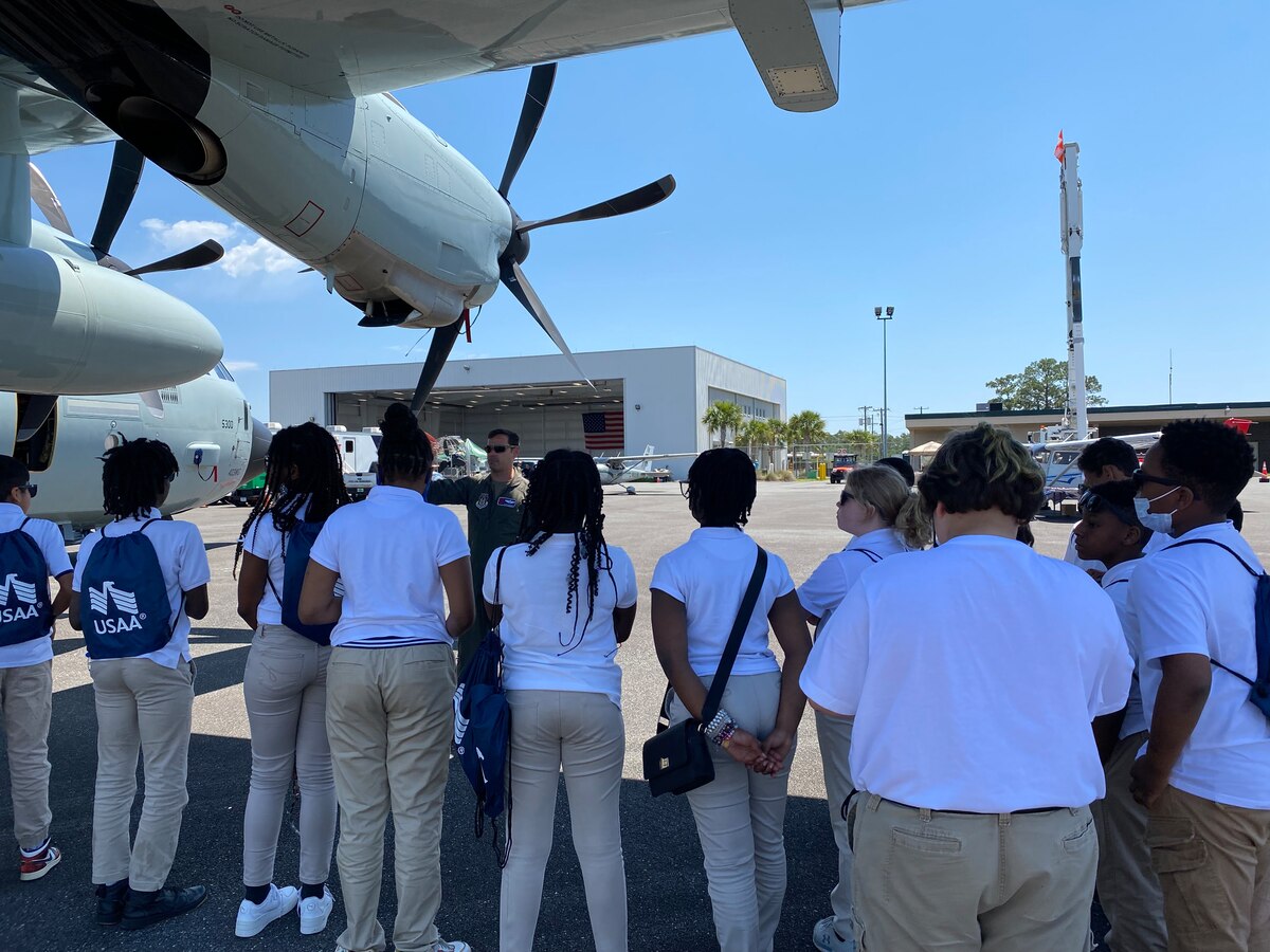 A group of students stand under the wing of a WC-130J Super Hercules listening to a military pilot explain the Hurricane Hunting mission.