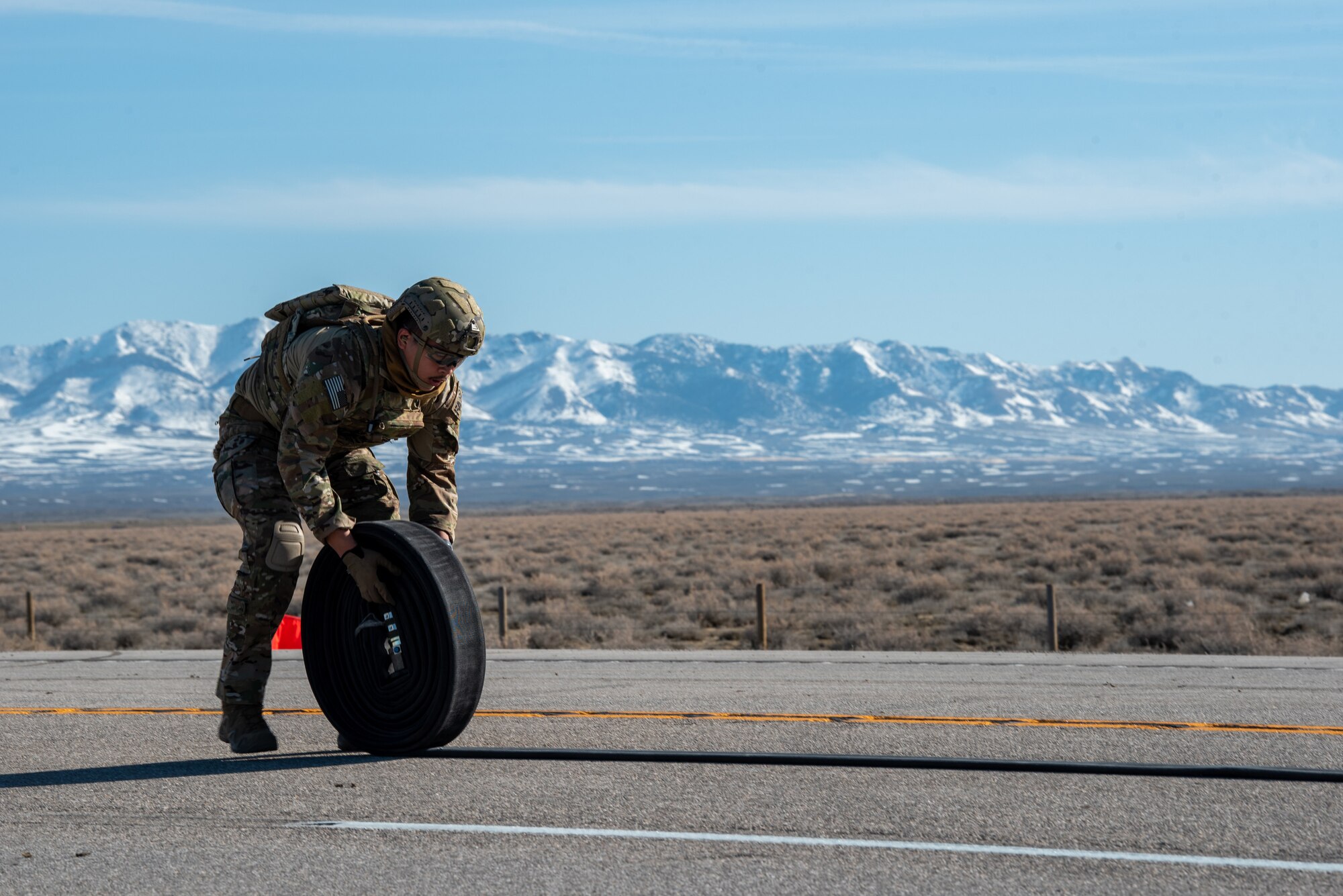 An Airman with the 1st Special Operations Wing rolls up a fuel hose after conducting Forward Arming and Refueling Point operations on Highway 287 in Wyoming during Exercise Agile Chariot on April 30, 2023, honing capabilities linked to Agile Combat Employment. Instead of relying on large, fixed bases and infrastructure, ACE employs smaller, more dispersed locations and teams to rapidly move aircraft, pilots and other personnel as needed. Under ACE, millions of miles of public roads can serve as functional runways with Forward Arming and Refueling Points when necessary. (U.S. Air National Guard photo by Master Sgt. Phil Speck)
