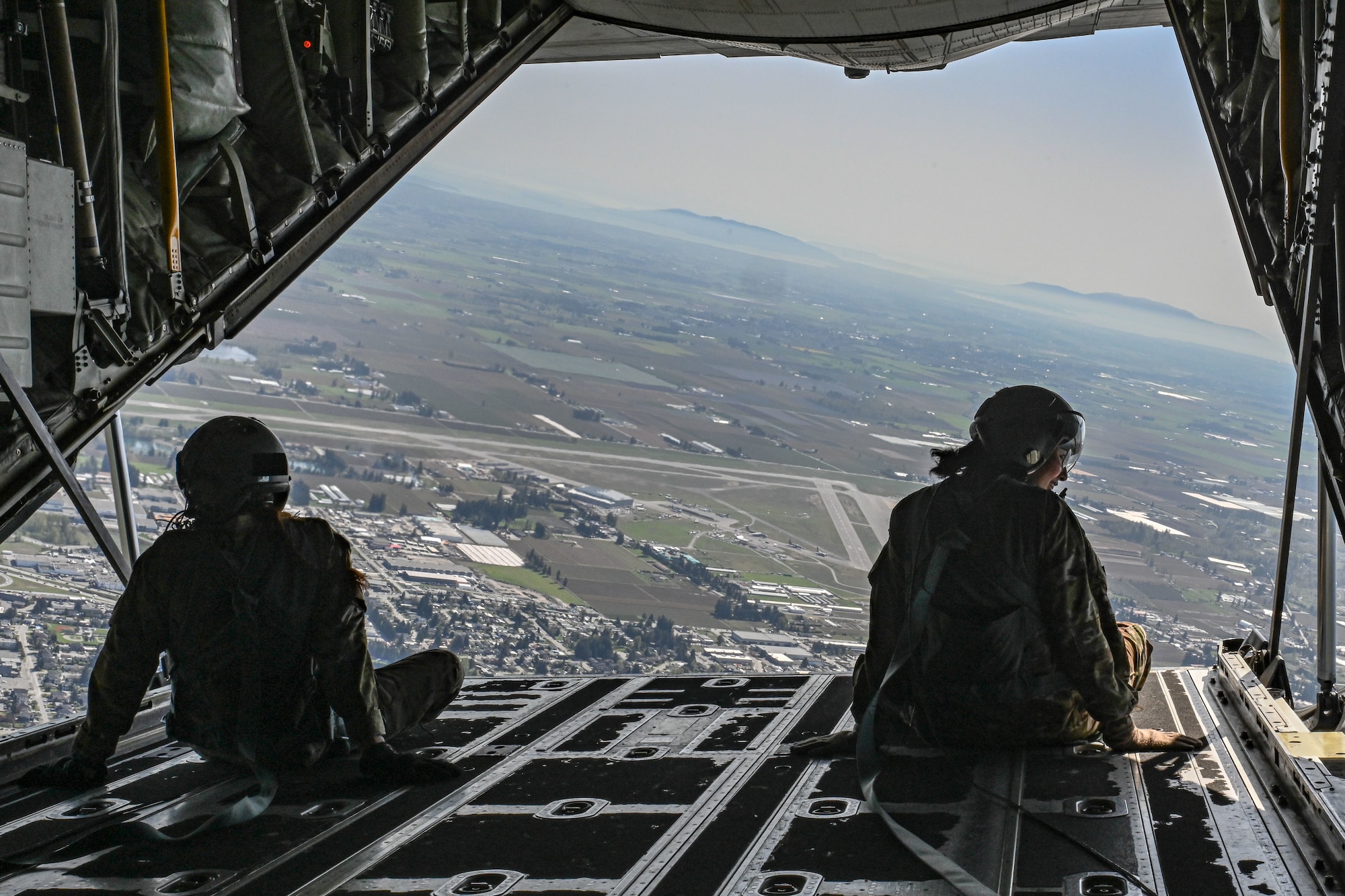 Airmen parachute jump out of the back of a C-130J Super Hercules