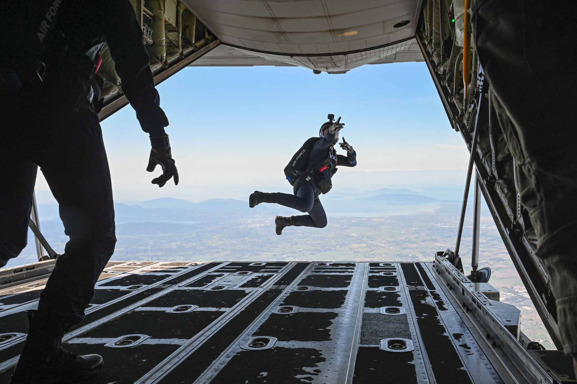 An airman parachute jumps out of the back of a C-130J Super Hercules