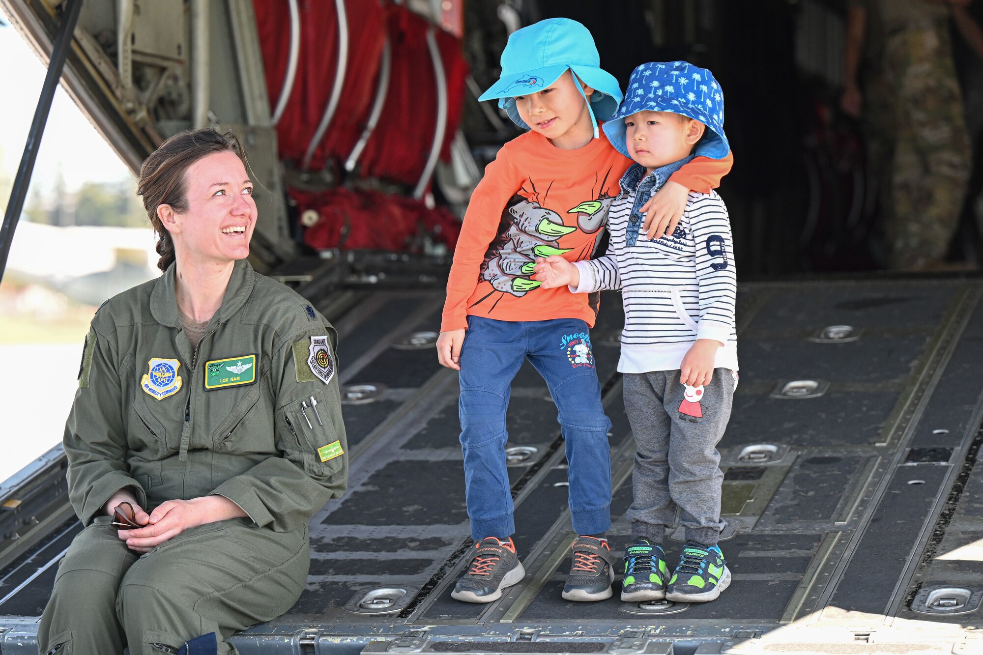 An airman speaks to children in the back of a C-130J Super Hercules