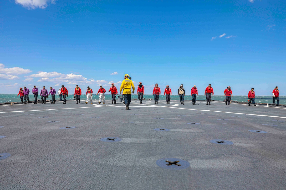 Sailors walk on the deck of a ship.