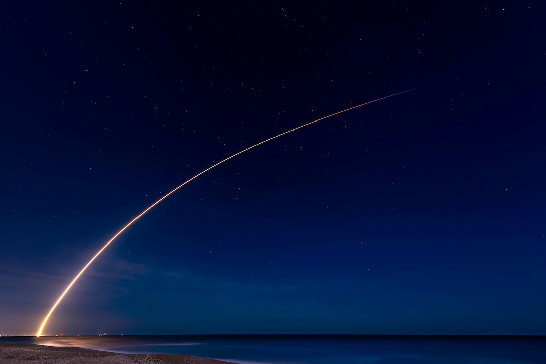 A rocket launches through the sky at night.