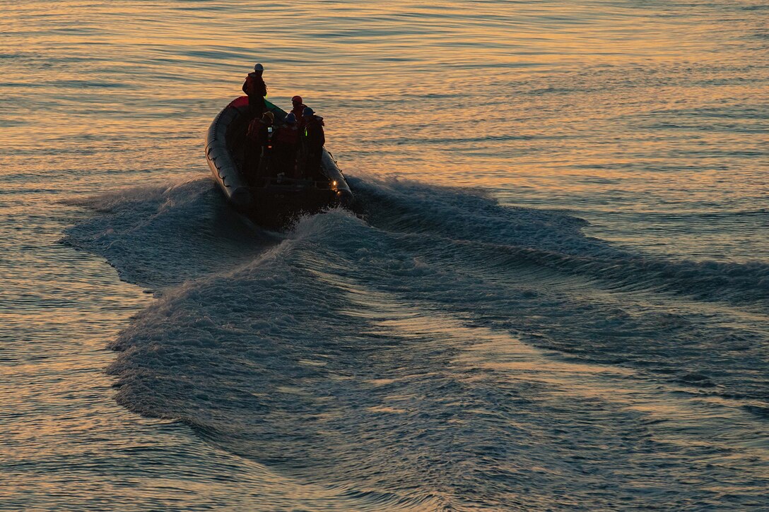 Sailors operate an inflatable boat sails in low sunlight.