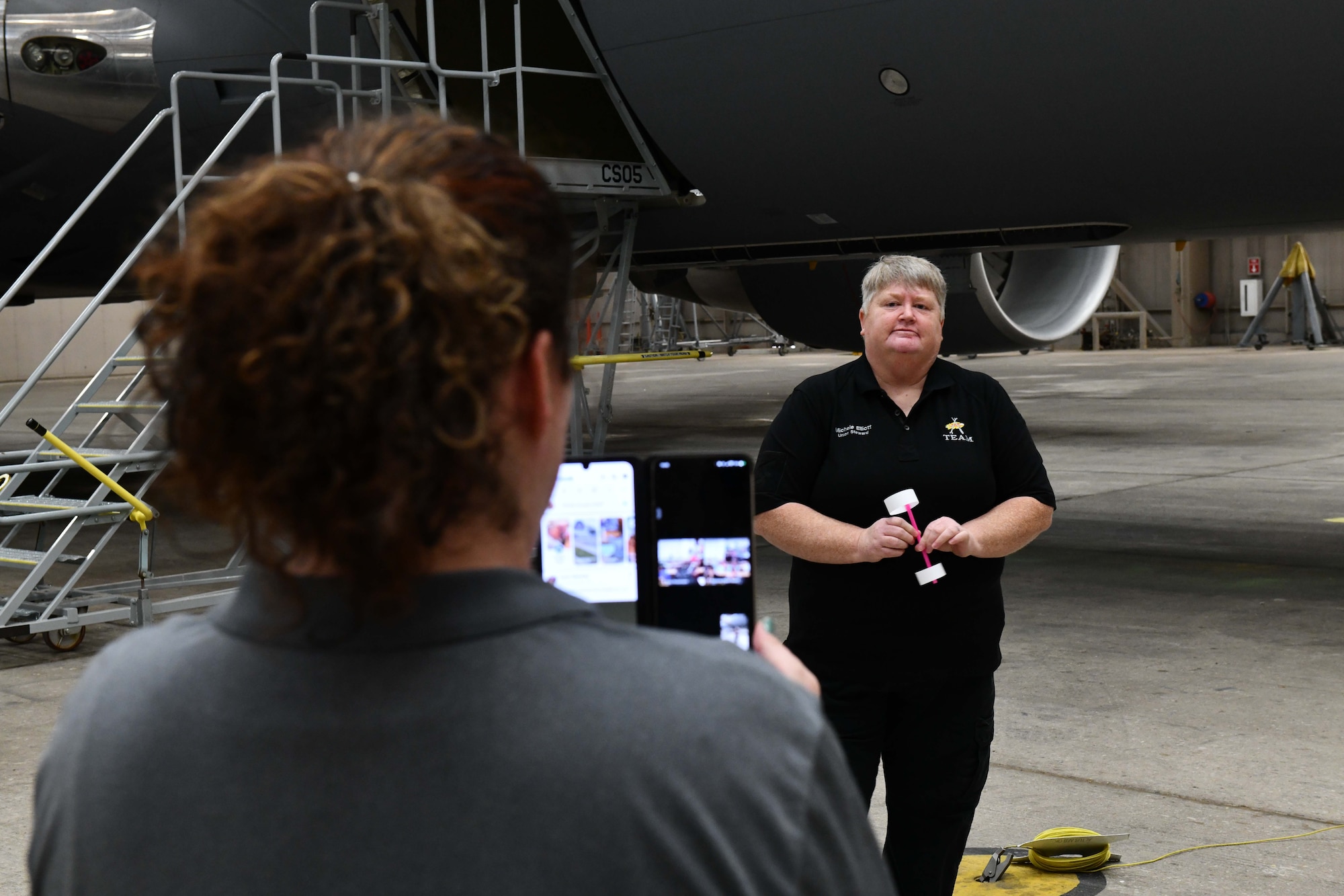 Kaitlyn Knott, 97th Maintenance Group, maintenance operations computer assistant, records a livestream of Michele Elliott, 97th Maintenance Squadron avionics technician, as she talks to students from Hill Field Elementary School in Clearfield, Utah, over a video call during a STEMtoSky event at Altus Air Force Base, Oklahoma, May 1, 2023. The live stream is a part of the STEMtoSky program, which is designed to provide an opportunity for Airmen to engage with students from across the country and teach science, technology, engineering and math aspects virtually through hands-on activities. (U.S. Air Force photo by Airman 1st Class Miyah Gray)