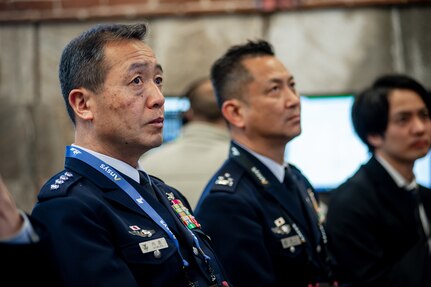Three Japan Air Self-Defense Force military officials listen to a briefing