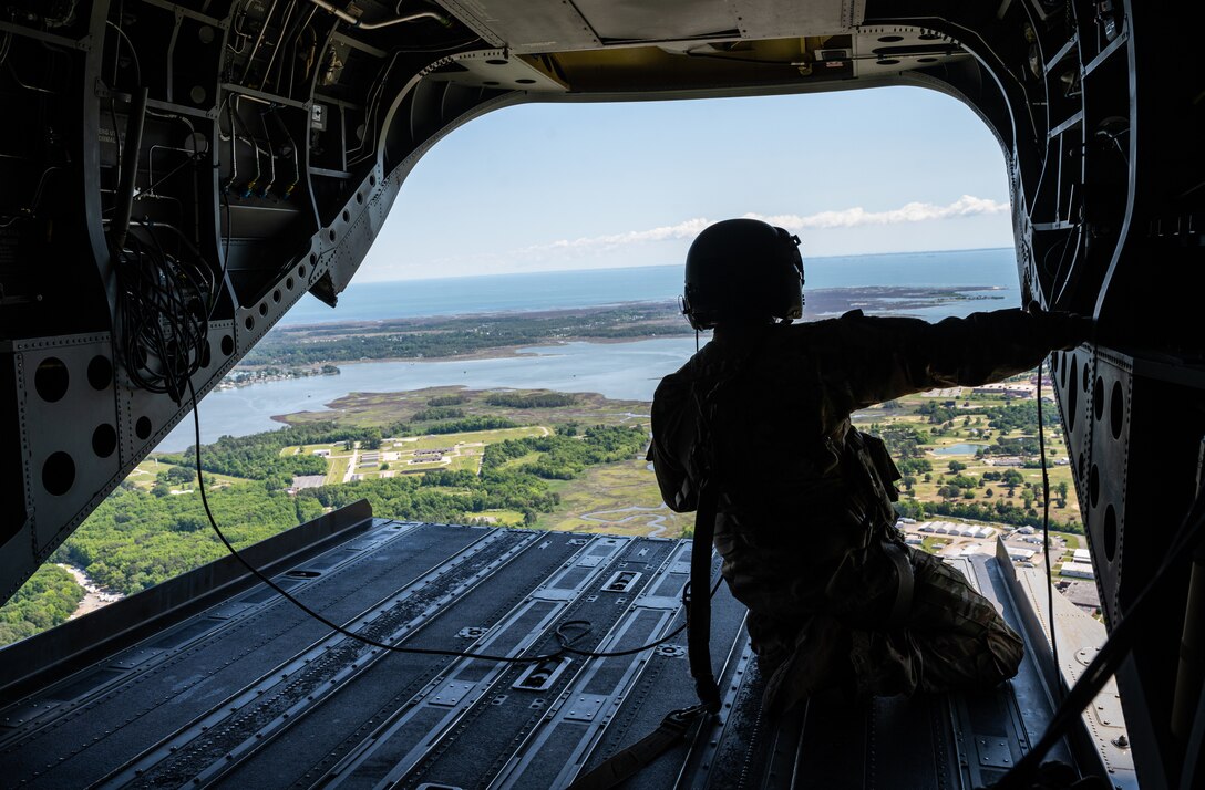A parachute team member looks out from the back of a helicopter.