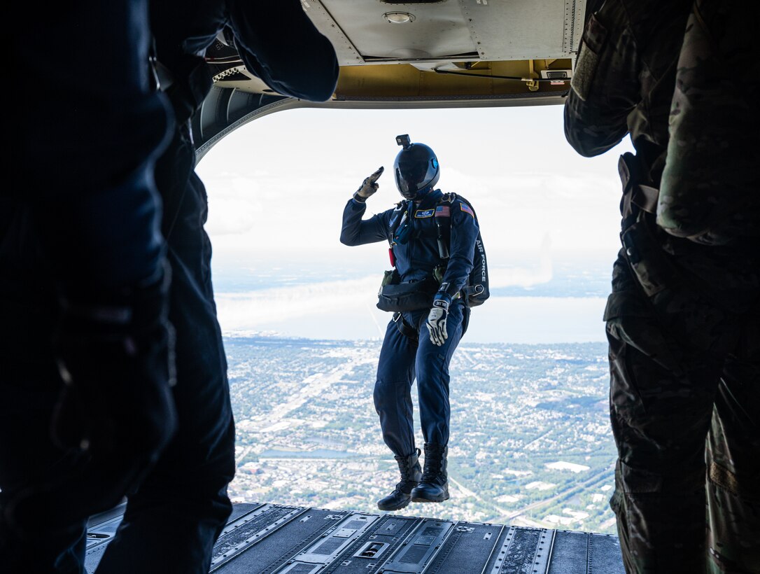 A parachute member jumps from a helicopter.