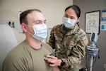 A military doctor checks a patient's heartbeat with a stethoscope.