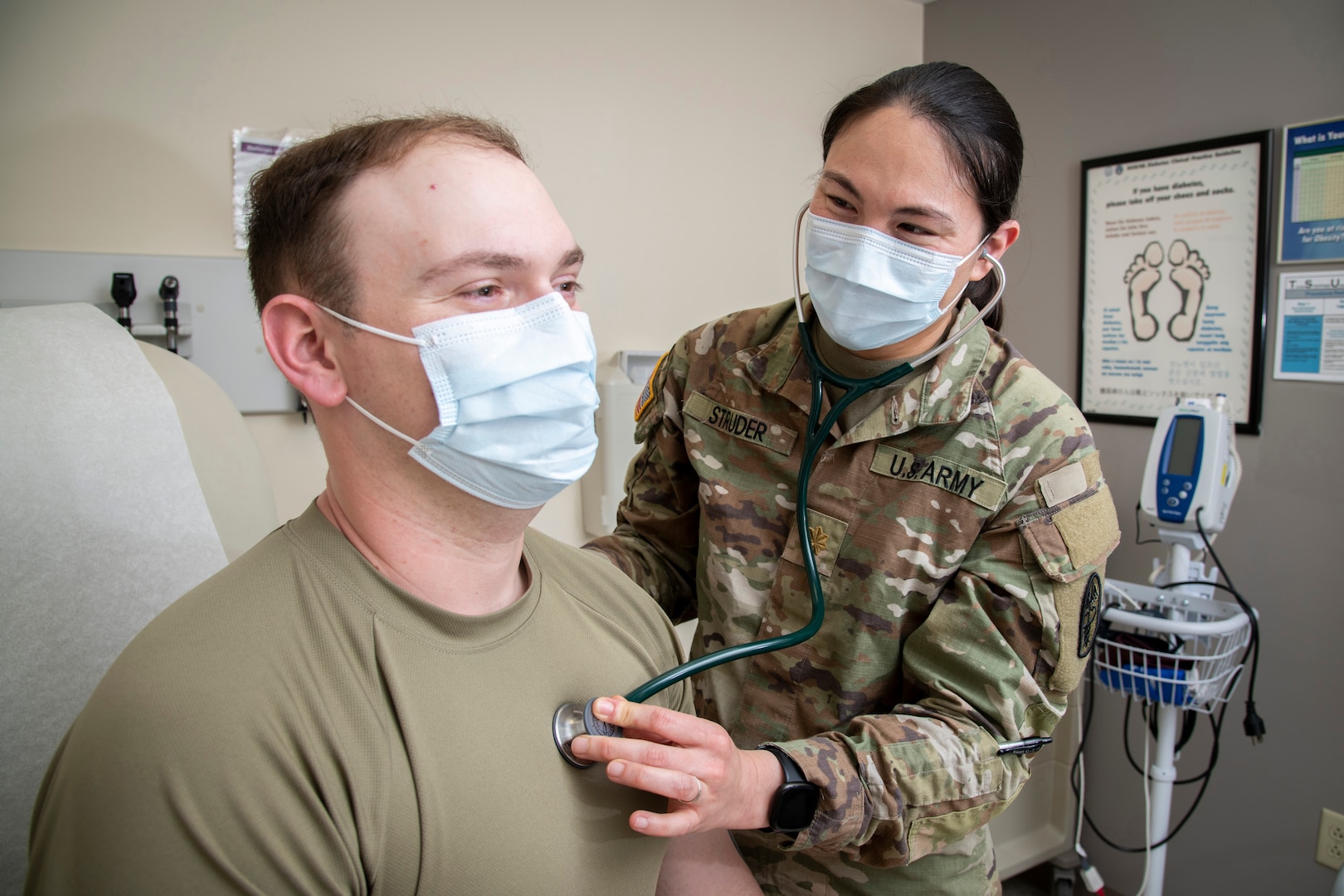 A military doctor checks a patient's heartbeat with a stethoscope.