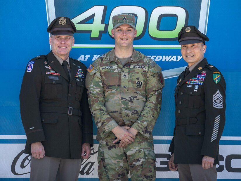 U.S. Army Brig. Gen. Dean Thompson, the commanding general of 353rd Civil Affairs Command (left), Staff Sgt. Adam Waddel, an M1 Armor Crewman assigned to Charlie Company, 1st Battalion, 16th Infantry Regiment, 1st Armored Brigade Combat Team, 1st Infantry Division (center), and Command Sgt. Maj. Clifford K. Lo, the command sergeant major of 353rd Civ. Aff. Cmd., gather for a photo at Kansas Speedway, Kansas City, Kan., May 7, 2023. Thompson and Lo held a reenlistment ceremony prior to the start of the AdventHealth 400 NASCAR race, where Soldiers from 1st Inf. Div. reenlisted in the middle of the speedway. (U.S. Army photo by Spc. Kenneth Barnet)