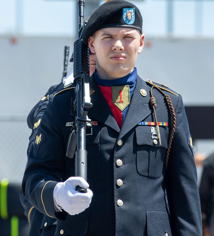 U.S. Army Spc. Grayson Powell, a geospatial intelligence imagery analyst assigned to Headquarters and Headquarters Battalion, 1st Infantry Division Artillery, 1st Infantry Division, marches onto the field during a reenlistment ceremony held at Kansas Speedway, Kansas City, Kan., May 7, 2023. Powell served as part of the 1st Infantry Division color guard during the AdventHealth 700 NASCAR race, presenting the national colors and participating in the pre-race reenlistment ceremony. (U.S. Army photo by Spc. Kenneth Barnet)