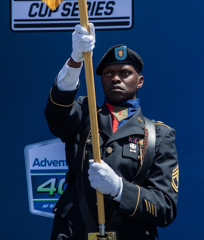 U.S. Army Sgt. 1st Class Trent Williams, a geospatial engineer assigned to Headquarters and Headquarters Battalion, 1st Infantry Division Artillery, 1st Infantry Division, presents the national colors during the national anthem for the AdventHealth 700 at Kansas Speedway, Kansas City, Kan., May 7, 2023. Williams led the color guard during the opening of the race and a 1st Infantry Division reenlistment ceremony prior. (U.S. Army photo by Spc. Kenneth Barnet)
