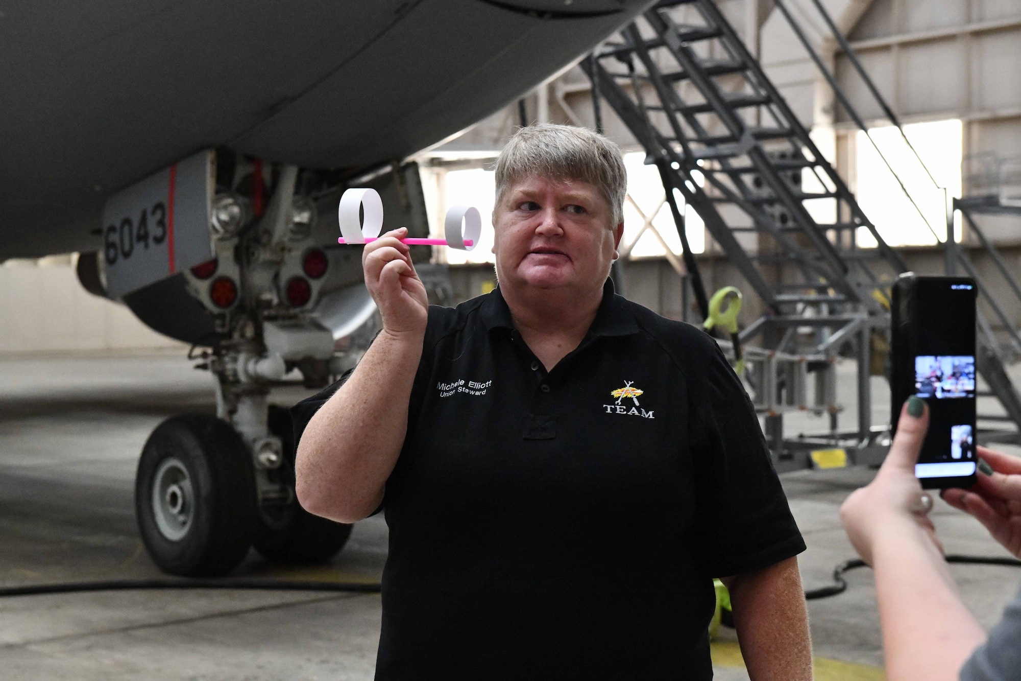 Michele Elliott, 97th Aircraft Maintenance Squadron avionics technician, shows off a hoop glider to a sixth-grade class over a livestream video call at Altus Air Force Base, Oklahoma, May 1, 2023. Elliot taught two sixth-grade classes from Hill Field Elementary School in Clearfield, Utah the concept of ‘lift’ by using hoop gliders, an alternative to traditional paper airplanes. (U.S. Air Force photo by Airman 1st Class Miyah Gray)