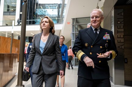 A woman walks next to man in uniform.