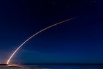 A rocket launches through the sky at night.