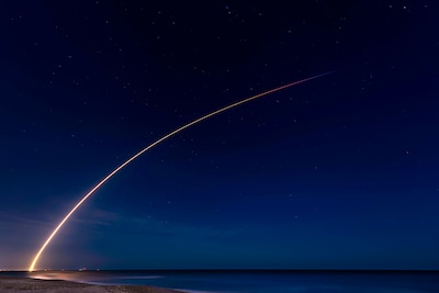 A rocket launches through the sky at night.