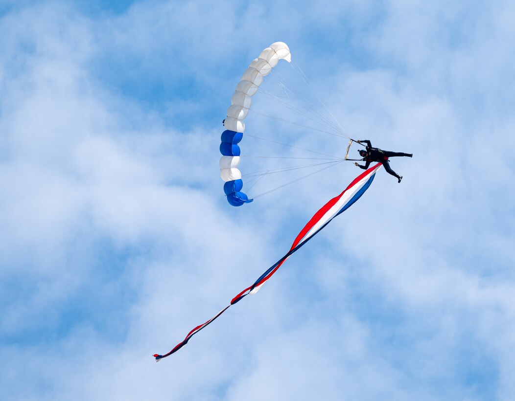 A parachute team member glides to the ground.