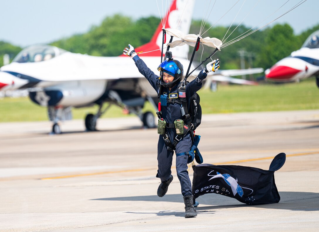 A parachute team member lands on a flight line.