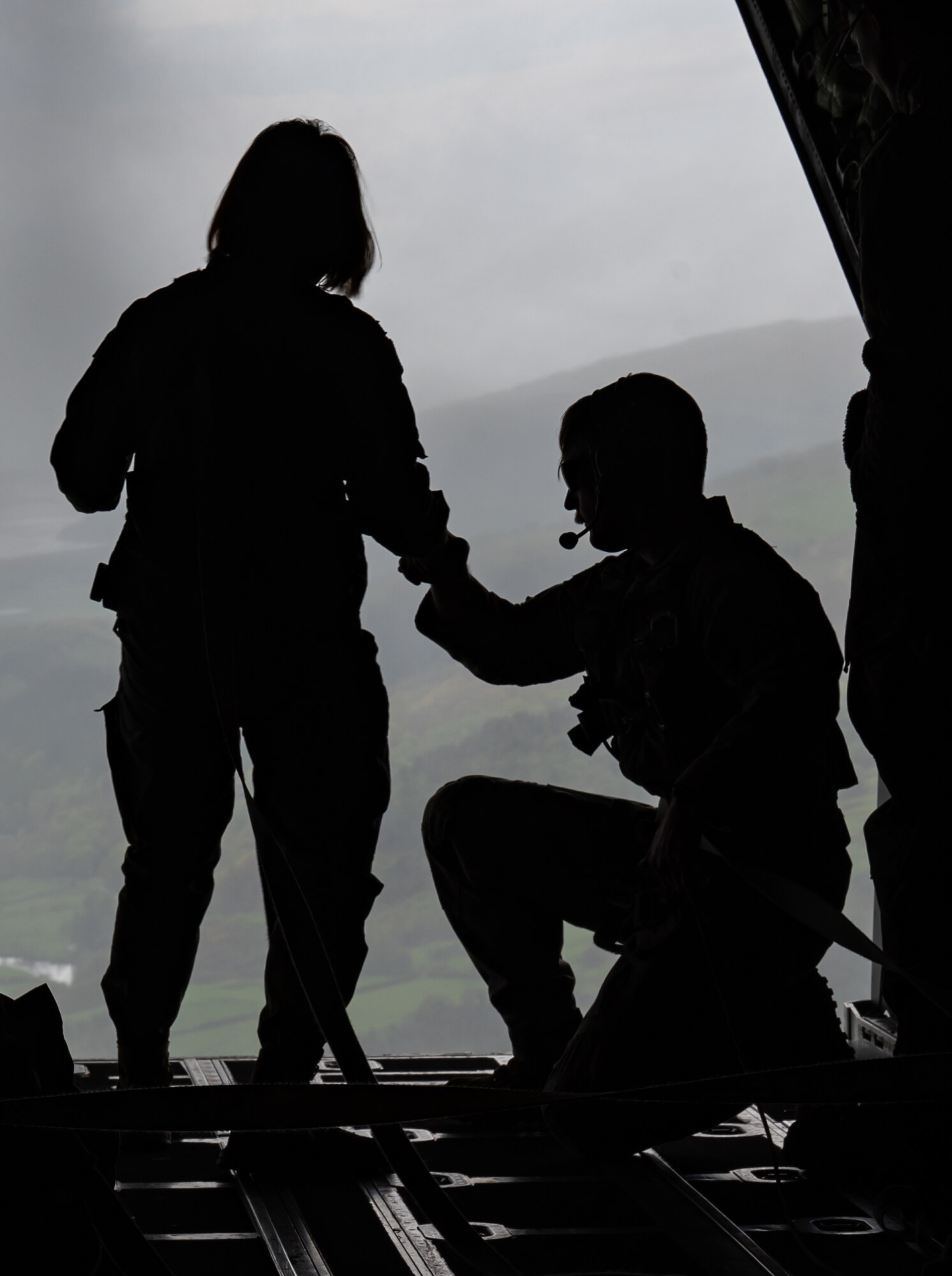 A U.S. Air Force Airmen assigned to Royal Air Force Lakenheath, is assisted by a MC-130J Commando II aircraft loadmaster assigned to the 352nd Special Operations Wing, England, May 5, 2023.