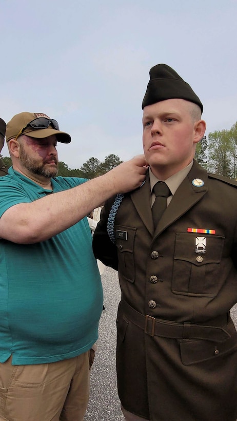 An Army Soldier receives blue infantry cord from his father.