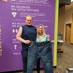 Pvt. Scott and fitness coach hold up old pair of jeans.