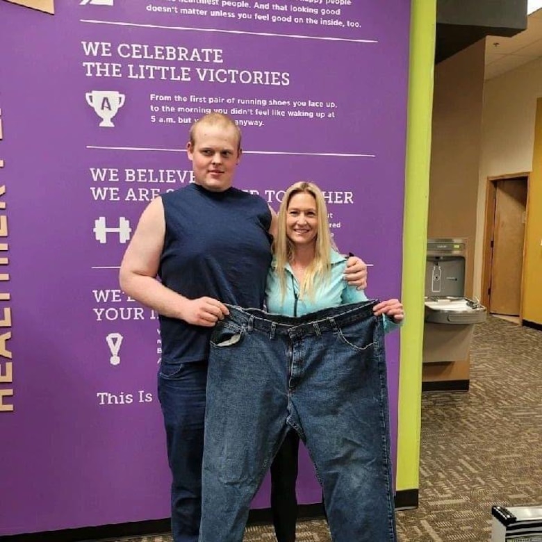 Pvt. Scott and fitness coach hold up old pair of jeans.