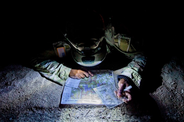 A National Guardsman examines a map in the dark using a headlamp during the Best Warrior Competition.