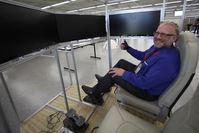 A man smiles while siting in a mock cockpit.