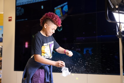 Trinity Moore, daughter of Carderock Deputy Command Information Officer Katrina Moore, pops a balloon in front of a high-speed camera during National Take Your Child to Work Day on April 27 in West Bethesda, Md. (U.S. Navy photo by Kristin Behrle)