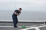 A crewmember on Coast Guard Cutter Healy takes a swing at the crew’s new biodegradable golf balls while on patrol in May 2022.