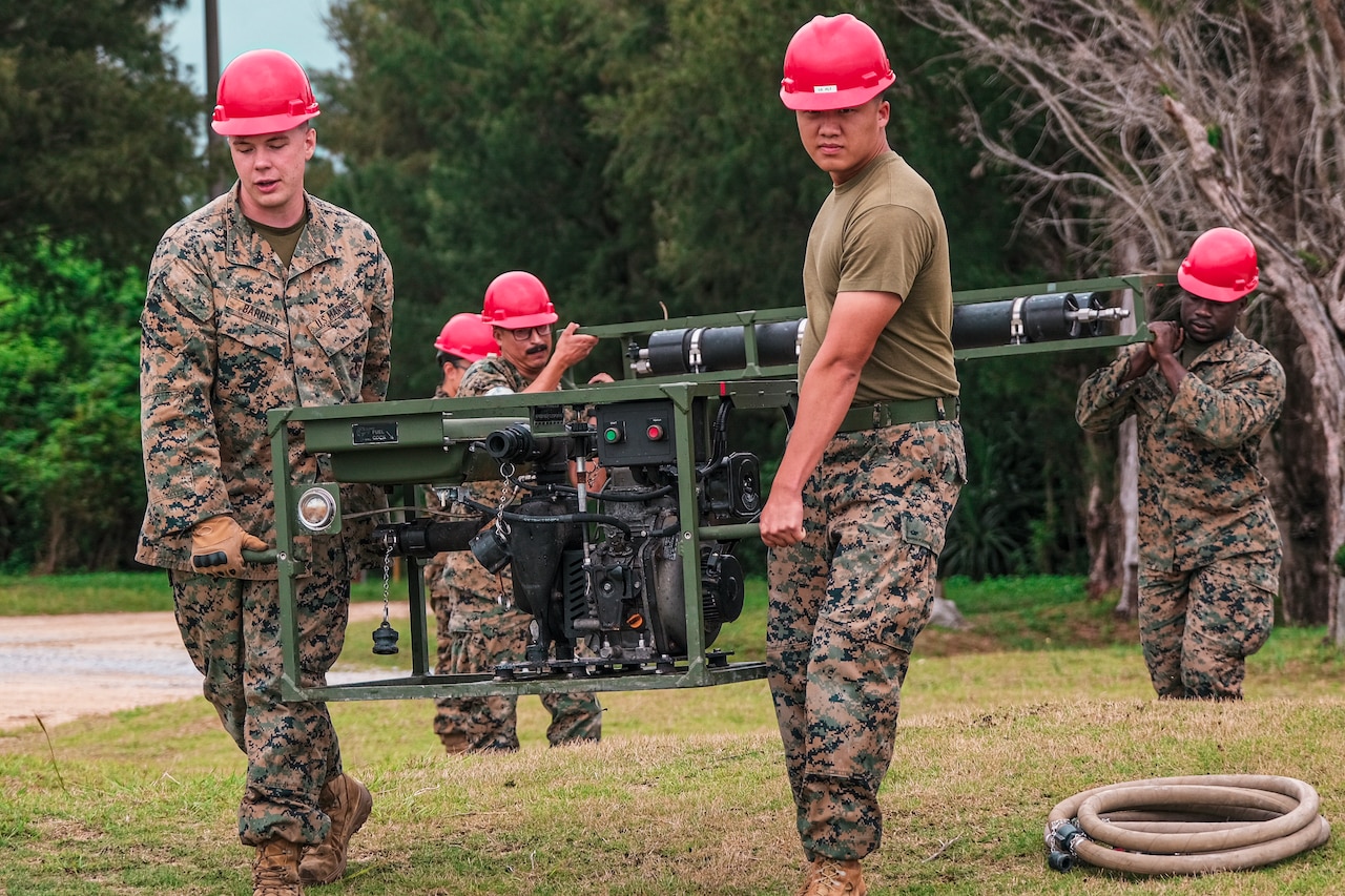 Marines carry parts of a platoon water purification system.