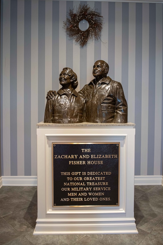 A bronze bust of two people stands atop a platform with a plaque below it.