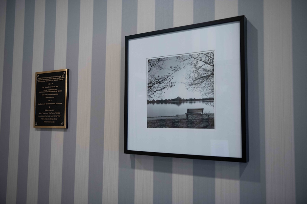 A framed photo hangs on a wall beside a small plaque.