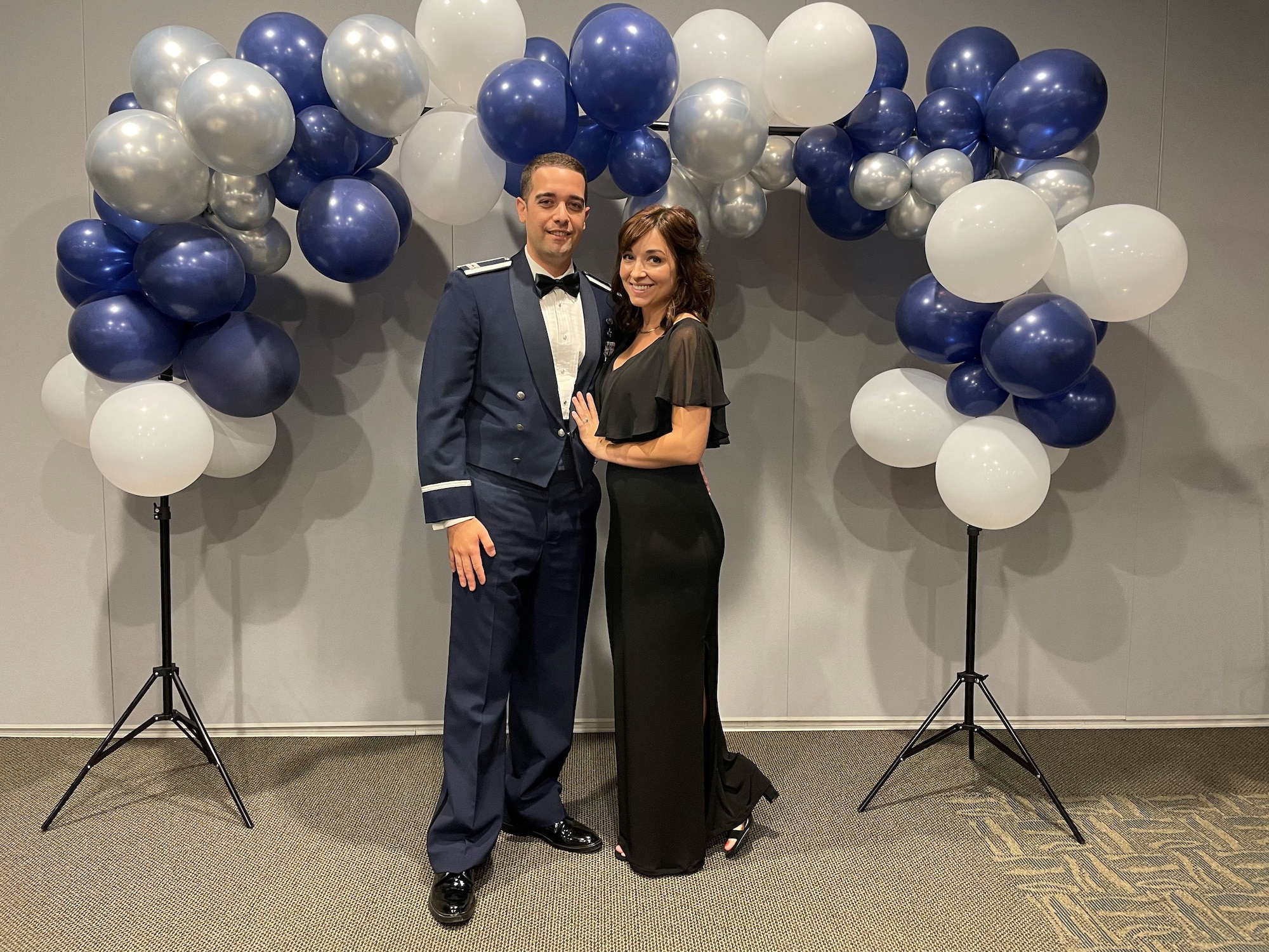 Capt. Shane Taylor and spouse Andrea Taylor pose together during a formal military event under a balloon arch.