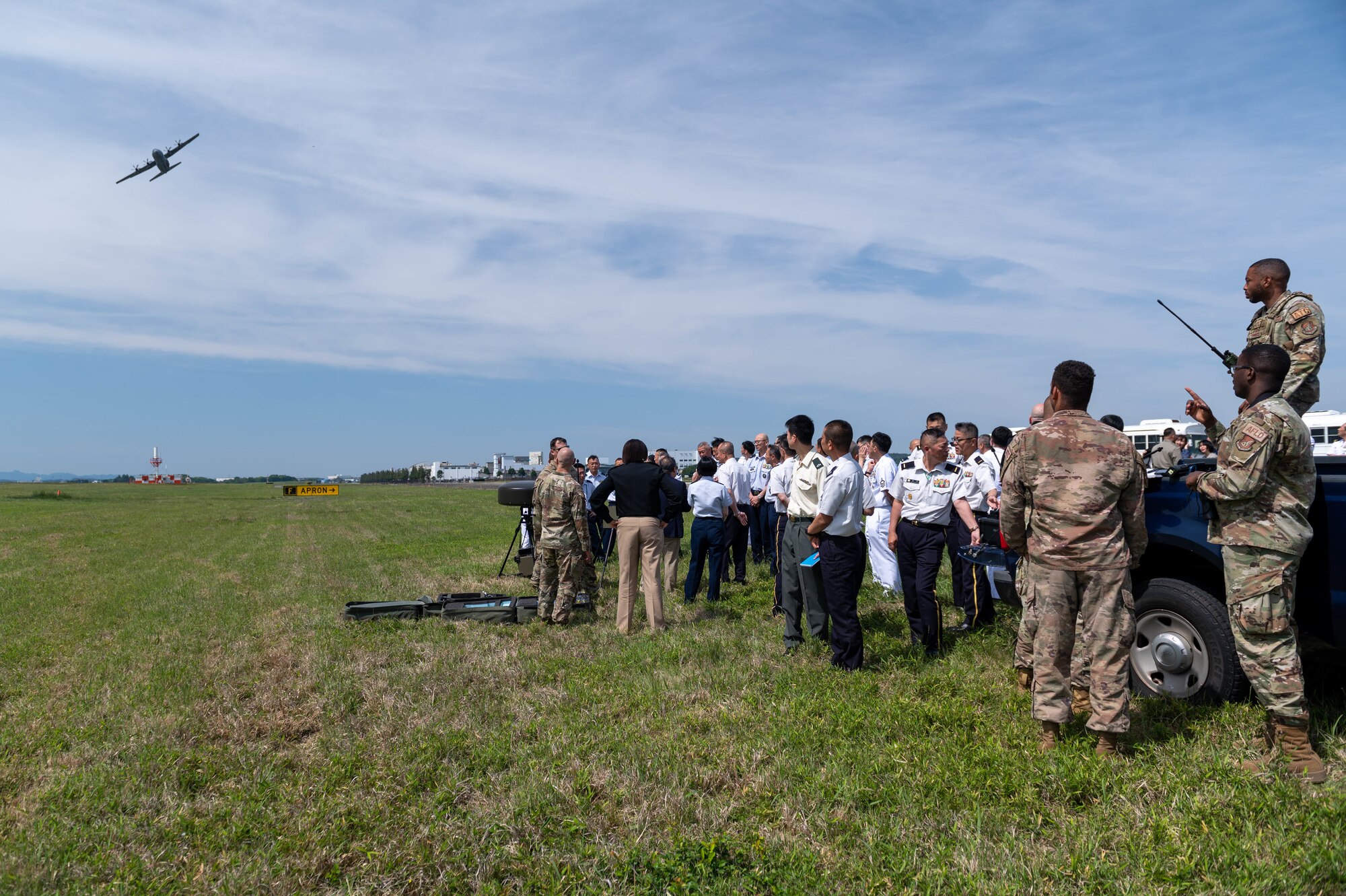 Airmen and attendees of the 2023 Senior Enlisted Leader Symposium watch as a C-130J Super Hercules flies overhead at Yokota Air Base, Japan.