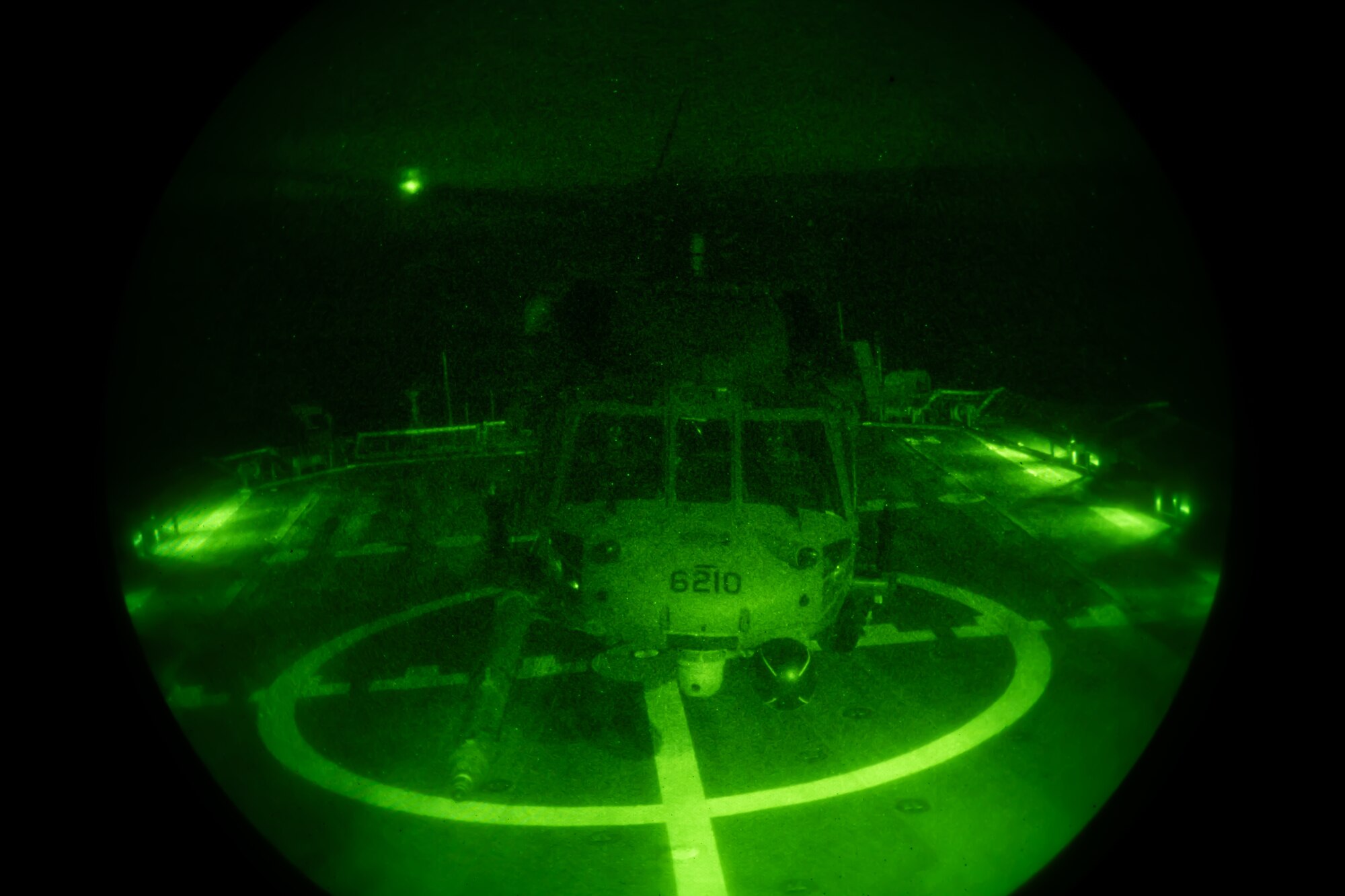A U.S. Air Force HH-60G Pave Hawk with the 33rd Rescue Squadron lands on the deck of a U.S. Coast Guard vessel during nighttime training off the coast of Okinawa, Japan, May 5, 2023. The training allows naval and flying units to coordinate and conduct operations with limited visibility. (U.S. Air Force photo by Senior Airman Cedrique Oldaker)