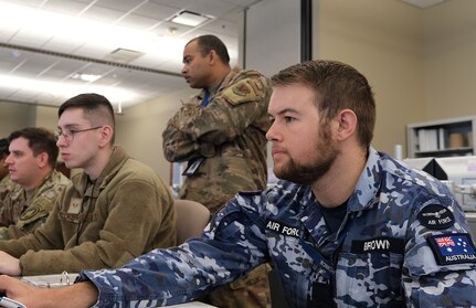 Uniformed U.S. Air Force and Royal Australian Air Force military personnel train at computers during the Air Operations Center Initial Qualification Training Course at Hurlburt Field, Florida.