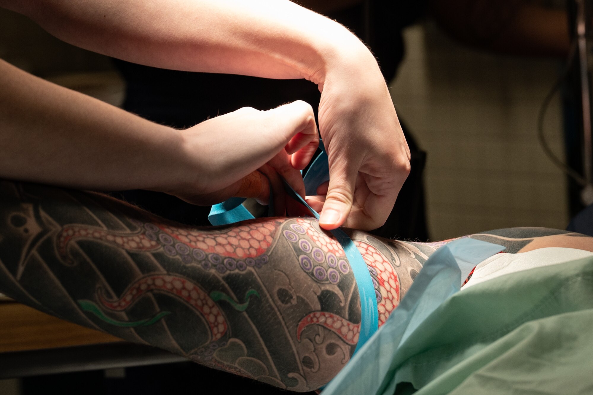 A close up of hands tending to a band around an arm