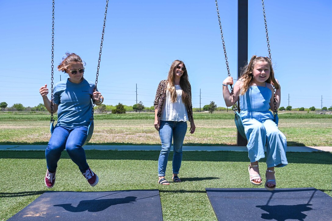 Trisha Fleishman, 97th Civil Engineering Squadron water quality program manager, pushes her daughters, Layla (left) and Margie (right), on a swing set at Altus Air Force Base, Oklahoma, May 4, 2023. Women make up 28.7% of the civilian workforce in the U.S. Air Force. (U.S. Air Force photo by Senior Airman Kayla Christenson)