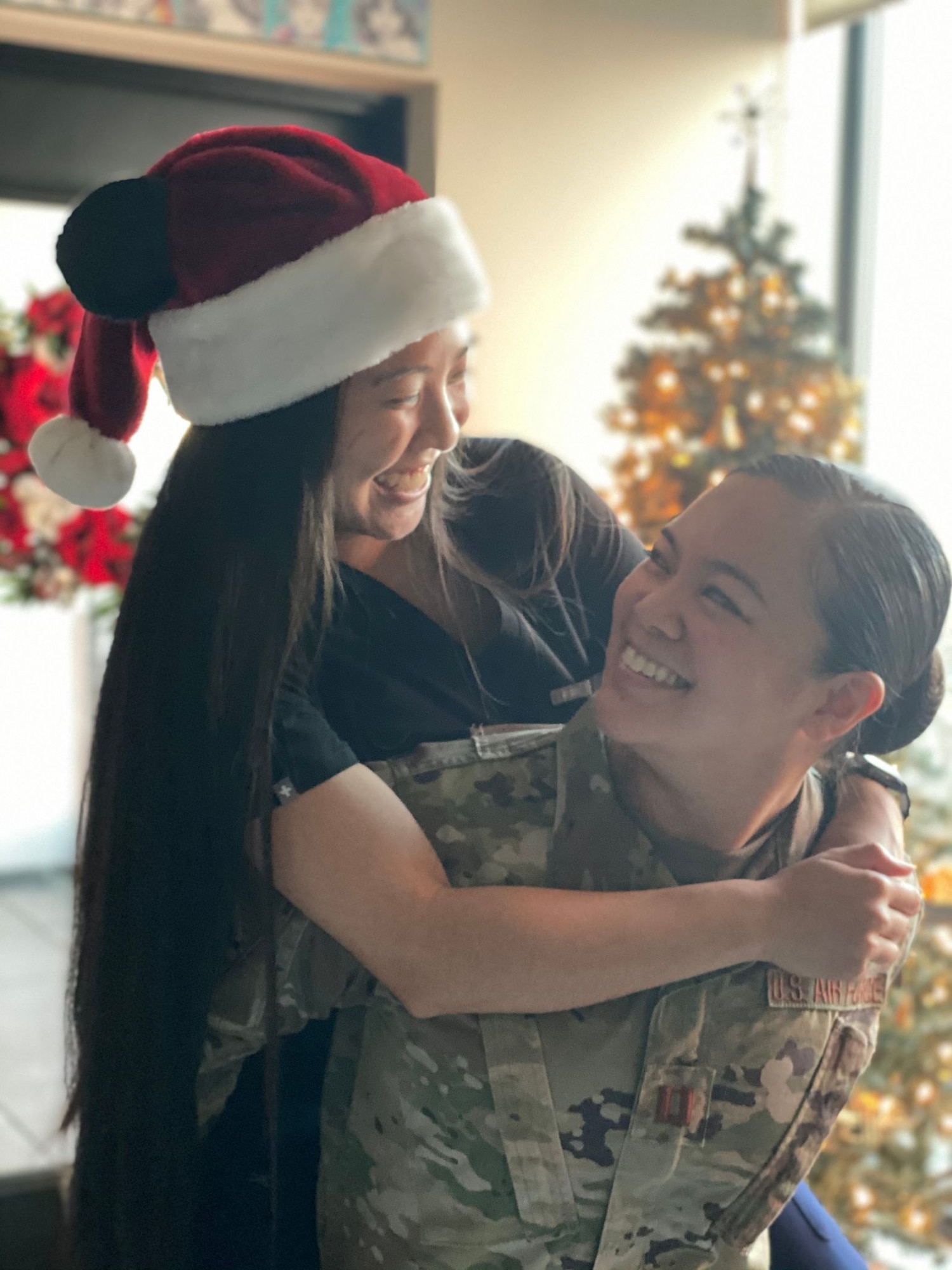 Capt. Joi Renee Athanaxay and her spouse, xxxx pose for a photo with with a playful piggyback ride.