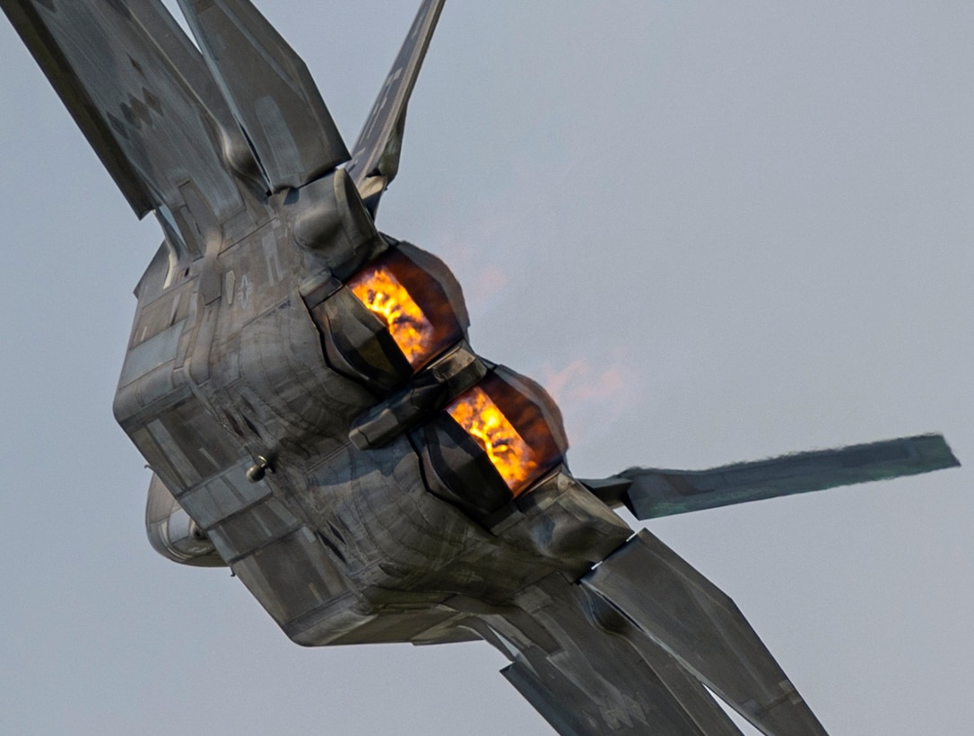 An aircraft flies on its side displaying flames from the back.