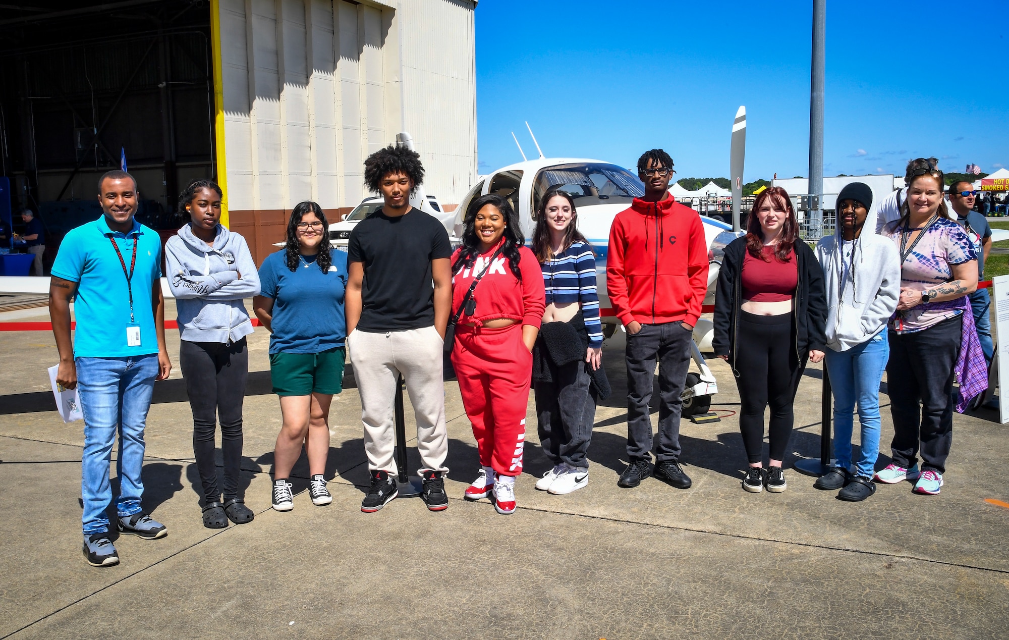 Students pose for group photo in front of aircraft static display.
