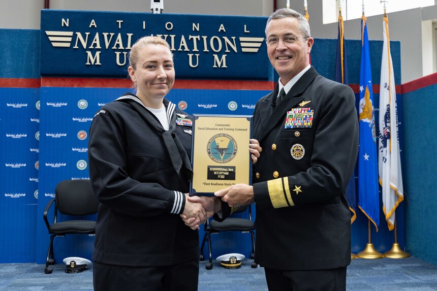 Rear Adm. Pete Garvin, right, commander, Naval Education and Training Command (NETC), awards a plaque to Aviation Ordnanceman First Class Amy L. Morris, assigned to Surface Combat Systems Training Command San Diego, California, one of NETC’s fiscal year 2022 Sailor of the Year (SOY) finalists, during NETC’s SOY announcement and award ceremony at the National Naval Aviation Museum in Pensacola, Florida, May 11, 2023. NETC's mission is to recruit, train and deliver those who serve our nation, taking them from street-to-fleet by forging civilians into highly skilled, operational and combat ready warfighters. (United States Navy photo by Mass Communication Specialist 2nd Class Zachary Melvin)
